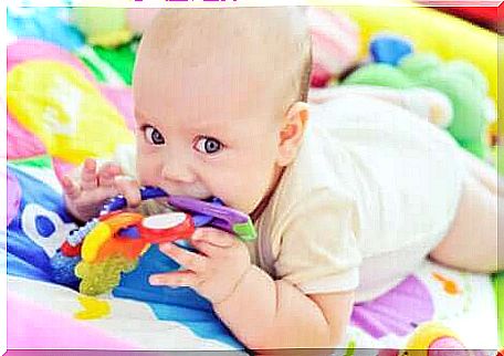 A playing baby lying on the floor.